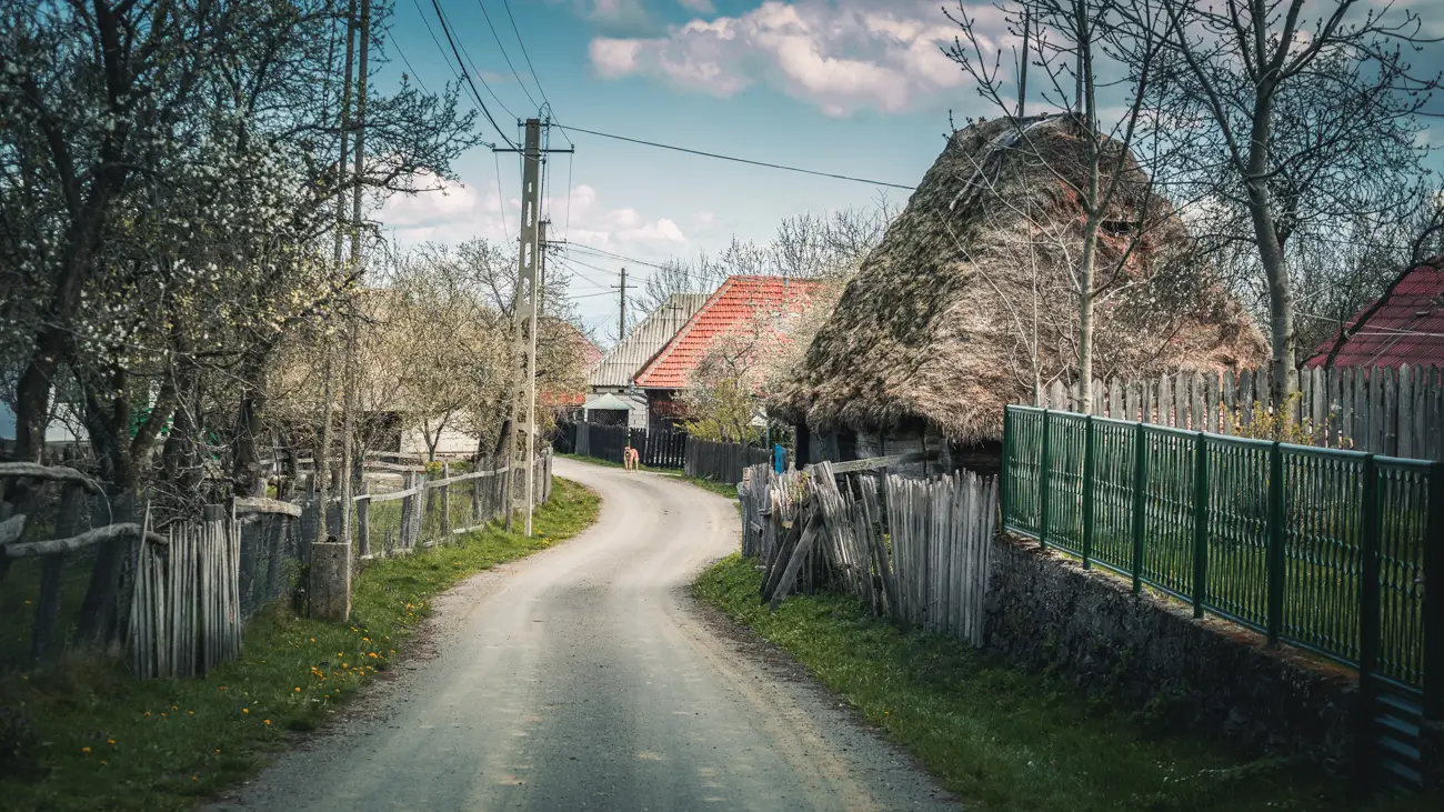 Narrow asphalted street with an old traditional barn.