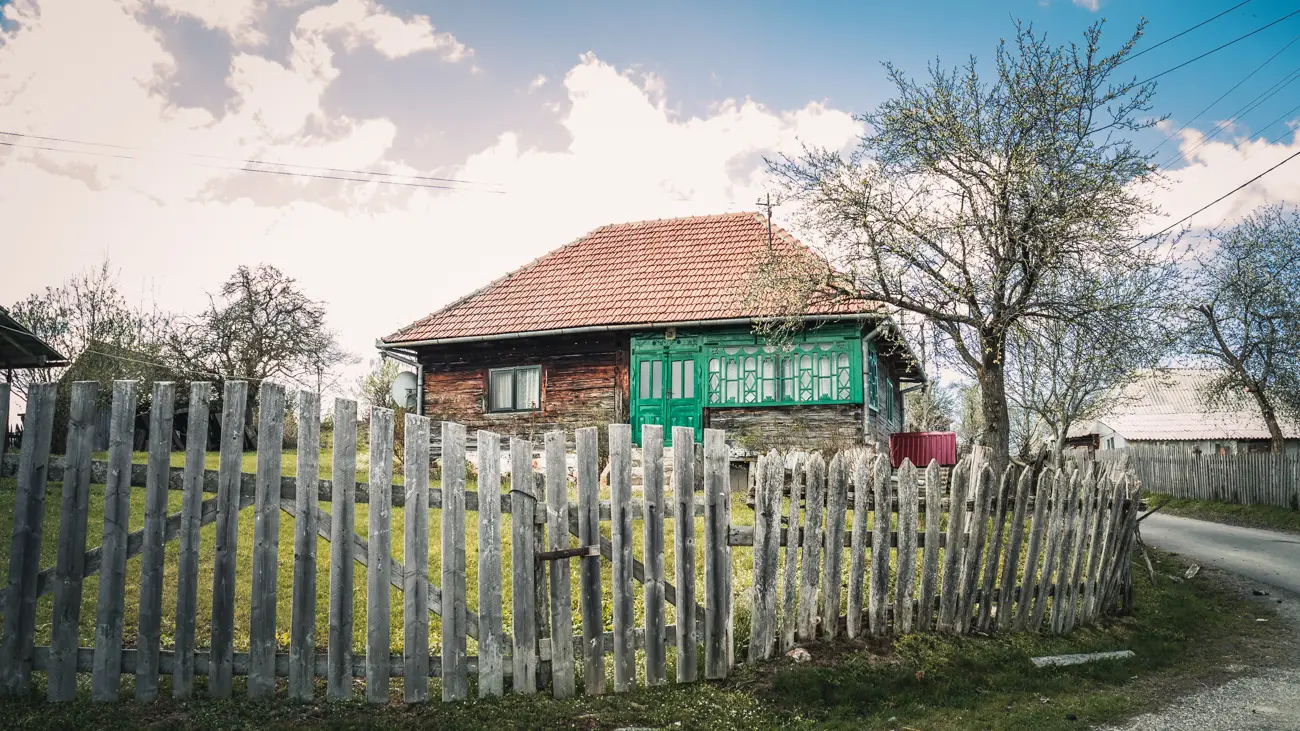 Wooden house with green windows and door.